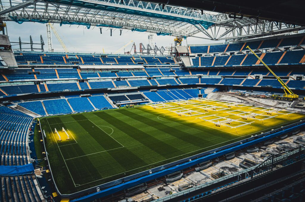 Aerial view of ongoing renovation at Santiago Bernabéu Stadium in Madrid, showcasing construction and vibrant seating arrangement.