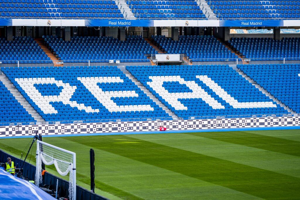 Empty seating area in Real Madrid's stadium with 'REAL' prominently displayed in white.