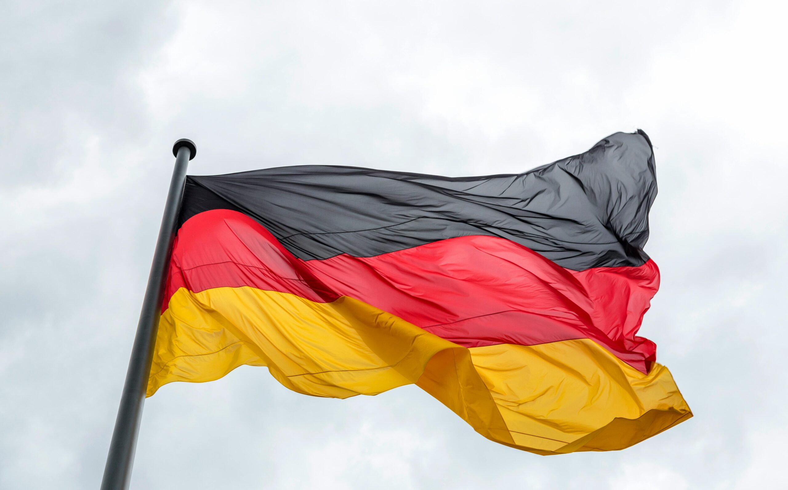 Waving German flag against a cloudy sky, featuring vibrant colors.