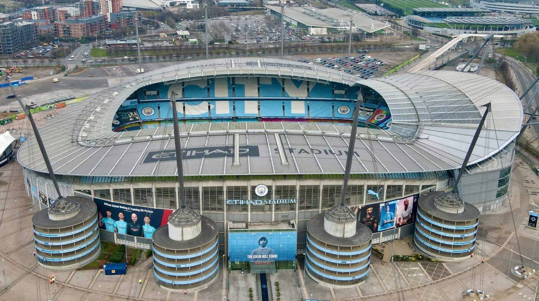 High-angle view of the iconic Etihad Stadium in Manchester, England, showcasing its modern architecture and surrounding cityscape.